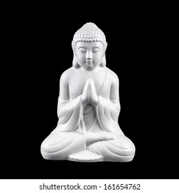 White, porcelain statuette of sitting meditating Buddha isolated on black