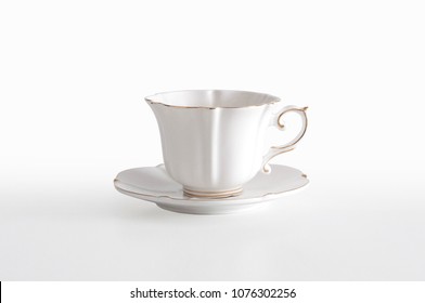 White porcelain tea cup with a golden line decoration and a saucer, on white background with clipping path, ready to cut out
