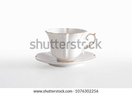 White porcelain tea cup with a golden line decoration and a saucer, on white background with clipping path, ready to cut out