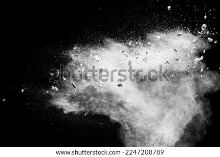 White powder with small stones on black background. Small granite rock stone fly on dust against dark background.