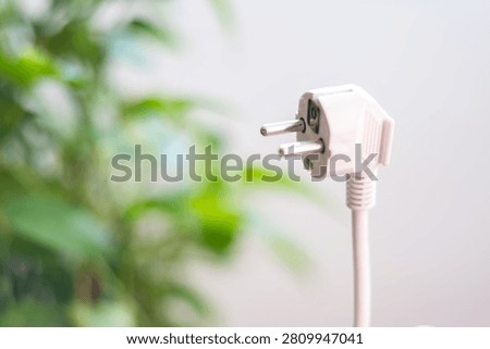 White power plug cable representing electricity consumption, energy efficiency, and cost savings, highlighting green energy and a reduced carbon footprint in a sustainable environment