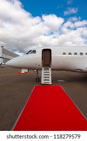 white private jet and open ladder, red carpet at airport, background blue sky