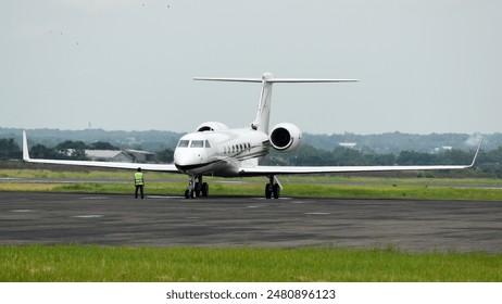 A white private twinjet on the apron and a marshaller - Powered by Shutterstock