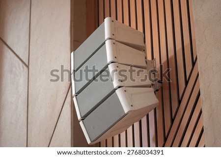 White professional line array speakers mounted on a wooden acoustic wall, high-end sound system equipment in a modern hall, auditorium, or house of worship interior.