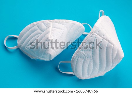 White protective masks on a blue background. Coronavirus (COVID-19) hysteria is leading to mass mask shortages in the beginning of 2020.