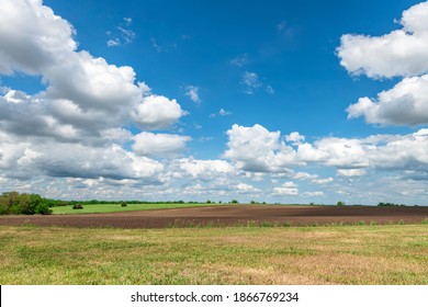 White, Puffy Clouds Moving Over Remote Dirt Road And Flat Lands In The Great Plains, Oklahoma.