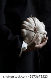 white pumpkin tied with string and hanging from one hand, spain