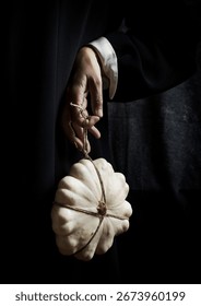white pumpkin tied with string and hanging from one hand IV, spain