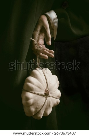 white pumpkin tied with string and hanging from one hand III, spain