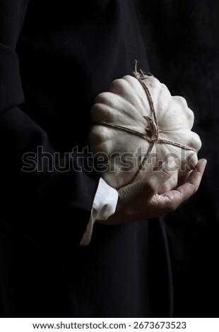 white pumpkin tied with string and hanging from one hand, spain