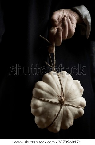 white pumpkin tied with string and hanging from one hand V, spain
