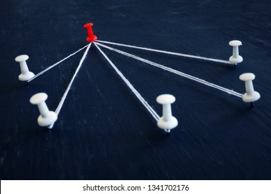 White push pins and red one connected by thread. Leadership, management and delegating.
