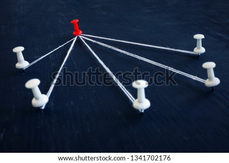 White push pins and red one connected by thread. Leadership, management and delegating.