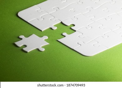 A White Puzzle With One Piece Missing But Not Fitting. Green Background, Copy Space. Selective Focus