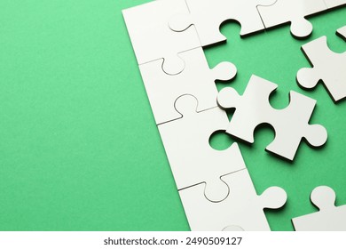 White puzzle pieces on green background, closeup - Powered by Shutterstock