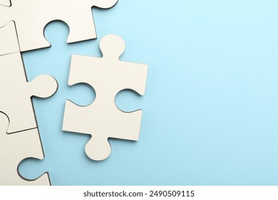 White puzzle pieces on light blue background, top view. Space for text - Powered by Shutterstock