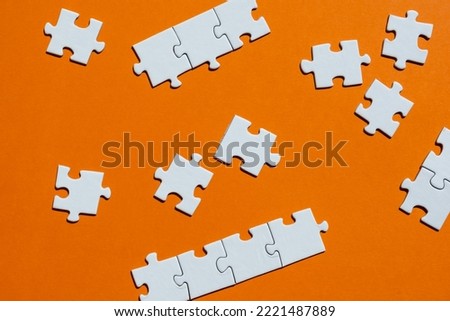 White puzzle pieces on the orange background. Concept of board game. Copy space for text, top view.