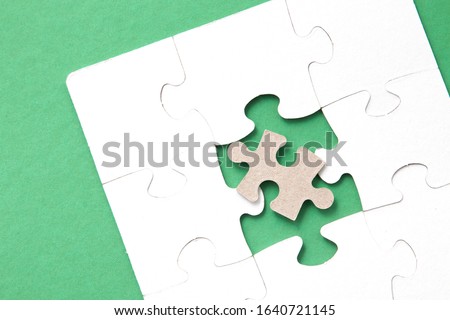 white puzzles on a pink background, folded puzzle, one piece is missing, instead a piece from another puzzle, an unsuitable part, unlike others, copy space