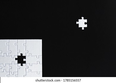 White Puzzles Are Stacked On Left Bottom Of Black Background. One Piece Located Separately On Social Distance. Concept Of Rejection, Inequality, Discrimination. Introvert Person. Coronavirus Epidemic.