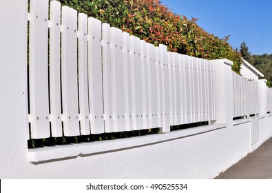 White Pvc Fence With Hedge Back In Residential Street 