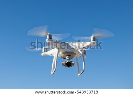 White quadrocopter hovers in the sky. Modern technology photo and video shooting.