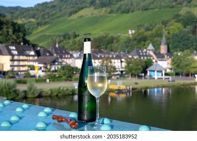White quality riesling wine in green bottle served on old bridge across Mosel river with view on old German town in sunny day