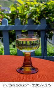 White Quality Riesling Wine Served In Yellow Swirl Wine Glass On Outdoor Terrace In Mosel River Wine Region, Germany