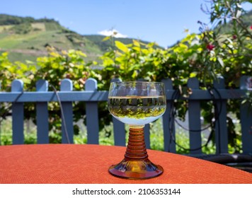 White Quality Riesling Wine Served In Yellow Swirl Wine Glass On Outdoor Terrace In Mosel River Wine Region, Germany