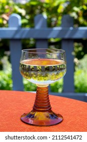 White Quality Riesling Wine Served In Yellow Swirl Wine Glass On Outdoor Terrace In Mosel River Wine Region, Germany