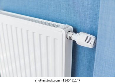 White radiator in an apartment with a blue walls.