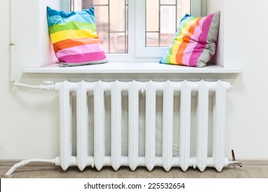 White radiator of central heating is in domestic room under window