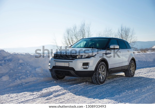 White Range Rover Evoque with a\
black roof on a winter road on the background of Zhiguli mountains\
of Samara region, Russia. Clear Sunny day 9 February\
2019