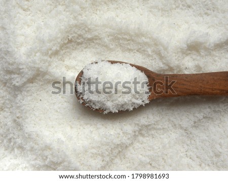 White raw dried desiccated coconut on wooden spoon