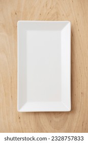 White rectangular ceramic plate on a wooden table, top view