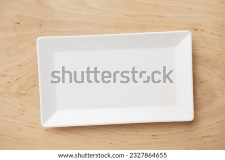 White rectangular ceramic plate on a wooden table, top view