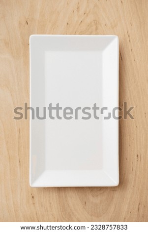 White rectangular ceramic plate on a wooden table, top view