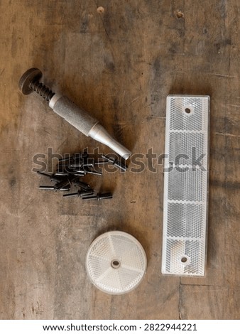 White Rectangular and Round Safety Reflectors with Rivets and Punch Tool on Wooden Workbench, Top View Flat Lay, Concept of Road Equipment Assembly, Maintenance, and Traffic Safety