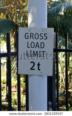 A white rectangular sign mounted on a post stating 