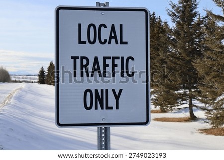 A white rectangular sign posted at a road entrance that reads, Local Traffic Only. The sign is white with a black pinstripe and black letters. It indicates restricted traffic area.