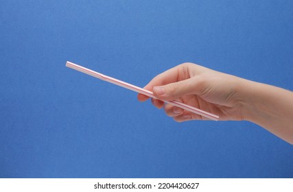 White And Red Bendy Straw Angled In Hand On A Blue Background