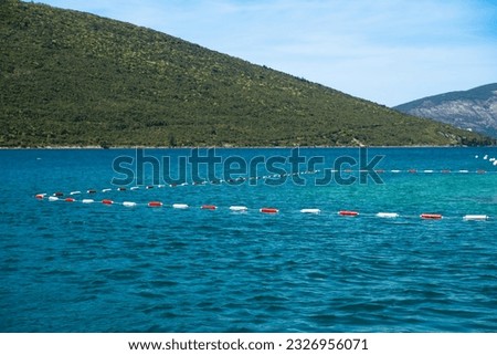 White and red buoys in the sea mark the swimming area. Adriatic Sea. Boko Kotor Bay.