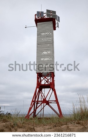 White and Red coloured Lighthouse Beacon with solar panels and ladder on the sandy beach on cloudy overcast day at Naissaar, Estonia, Europe