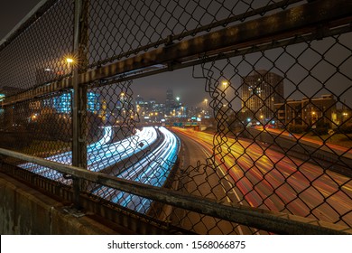 White and red light trails coming and going to downtown Chicago on a cloudy misty night viewed through an opening in a chain link fence guard rail on an overpass above highway or expressway at night. - Powered by Shutterstock