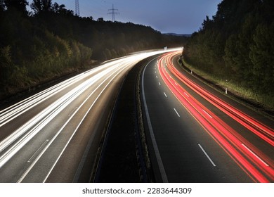 white and red traces of light from moving cars on highway at night six lines autobahn car road long exposure shot fast moving cars