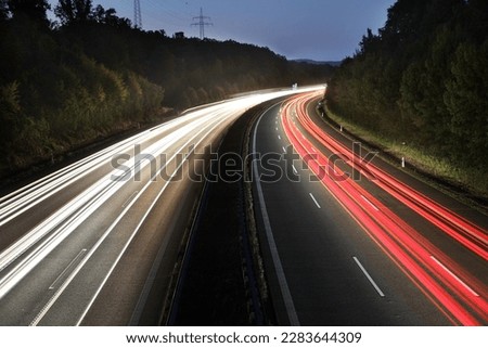 white and red traces of light from moving cars on highway at night six lines autobahn car road long exposure shot fast moving cars