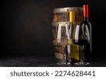 White and red wine bottles in front of wine barrel. With copy space