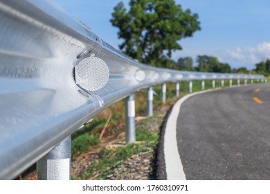 White reflective sign warn curve at night on the steel guard rail on the road or street in the countryside with blue sky in day time close-up.