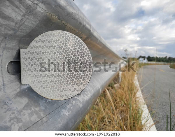 White reflective sign warn curve at night on\
the steel guard rail on the road or street in the countryside with\
blue sky in day time\
close-up.
