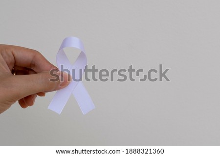 white ribbon on a woman's hand, represents the mental health prevention program. White January. world cancer prevention day. neutral space

