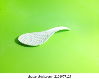 white rice scoop and made of heat-resistant plastic, has a texture to prevent the spoon from sticking with rice, photographed on an isolated green background